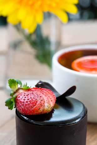 Close-up of a luxurious chocolate-covered strawberry with edible gold flakes on a white background
