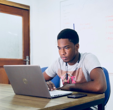 man in grey shirt using grey laptop computer