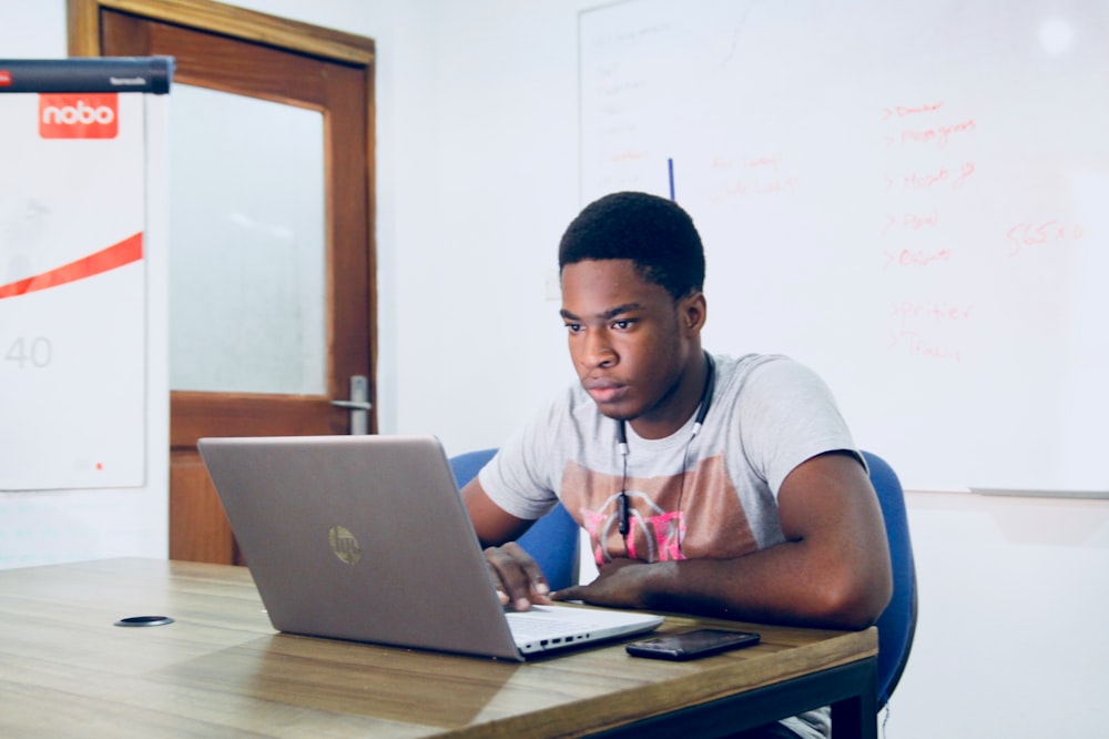 homem na camisa cinzenta usando o computador portátil cinzento