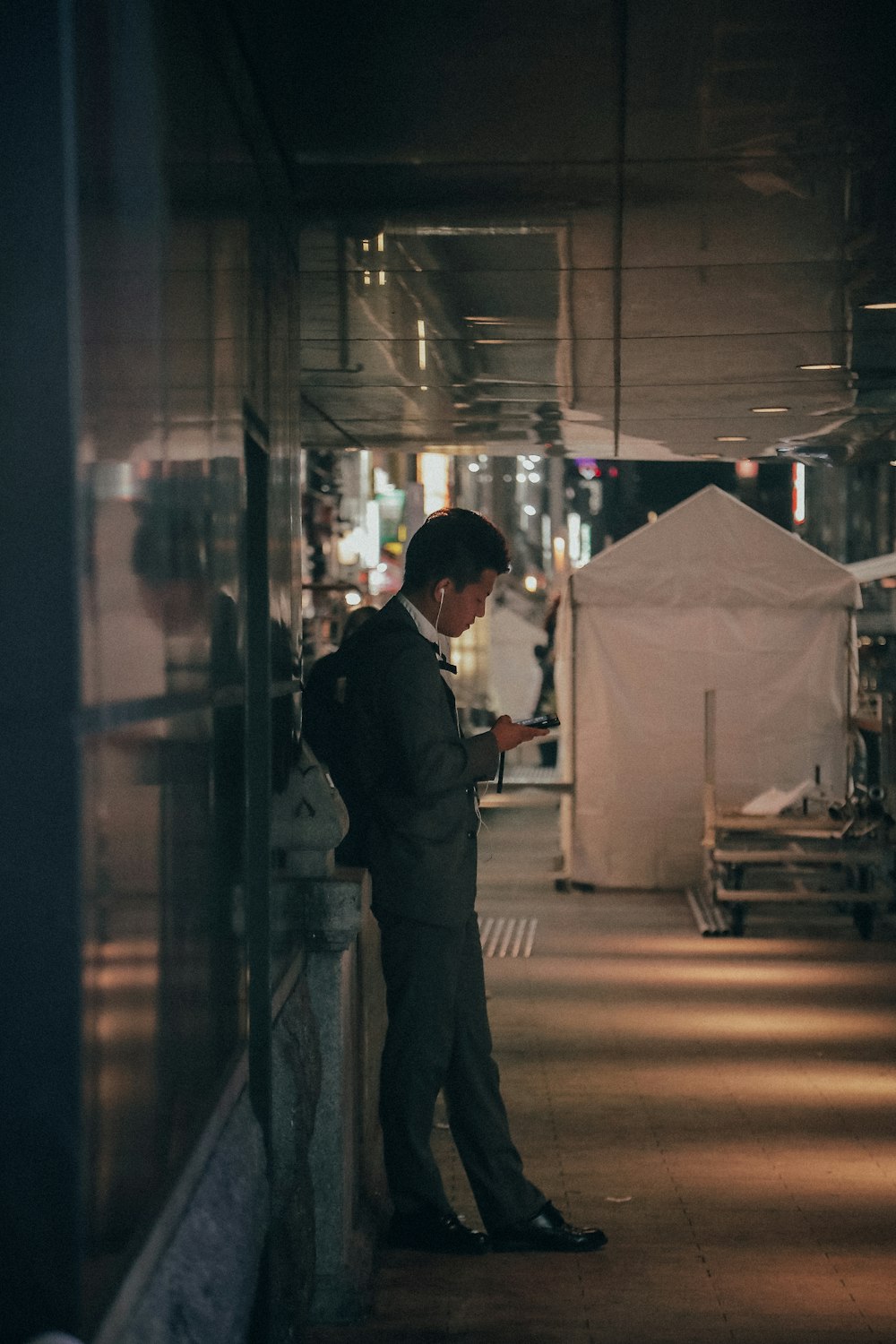 man standing beside glass builiding