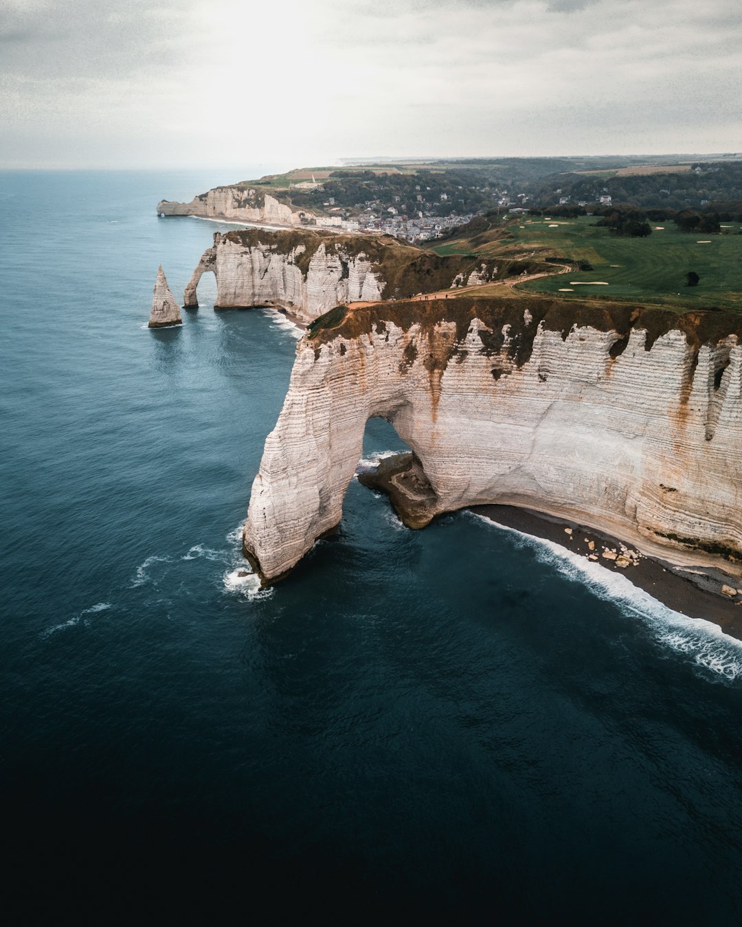 brown and green cliff and body of water