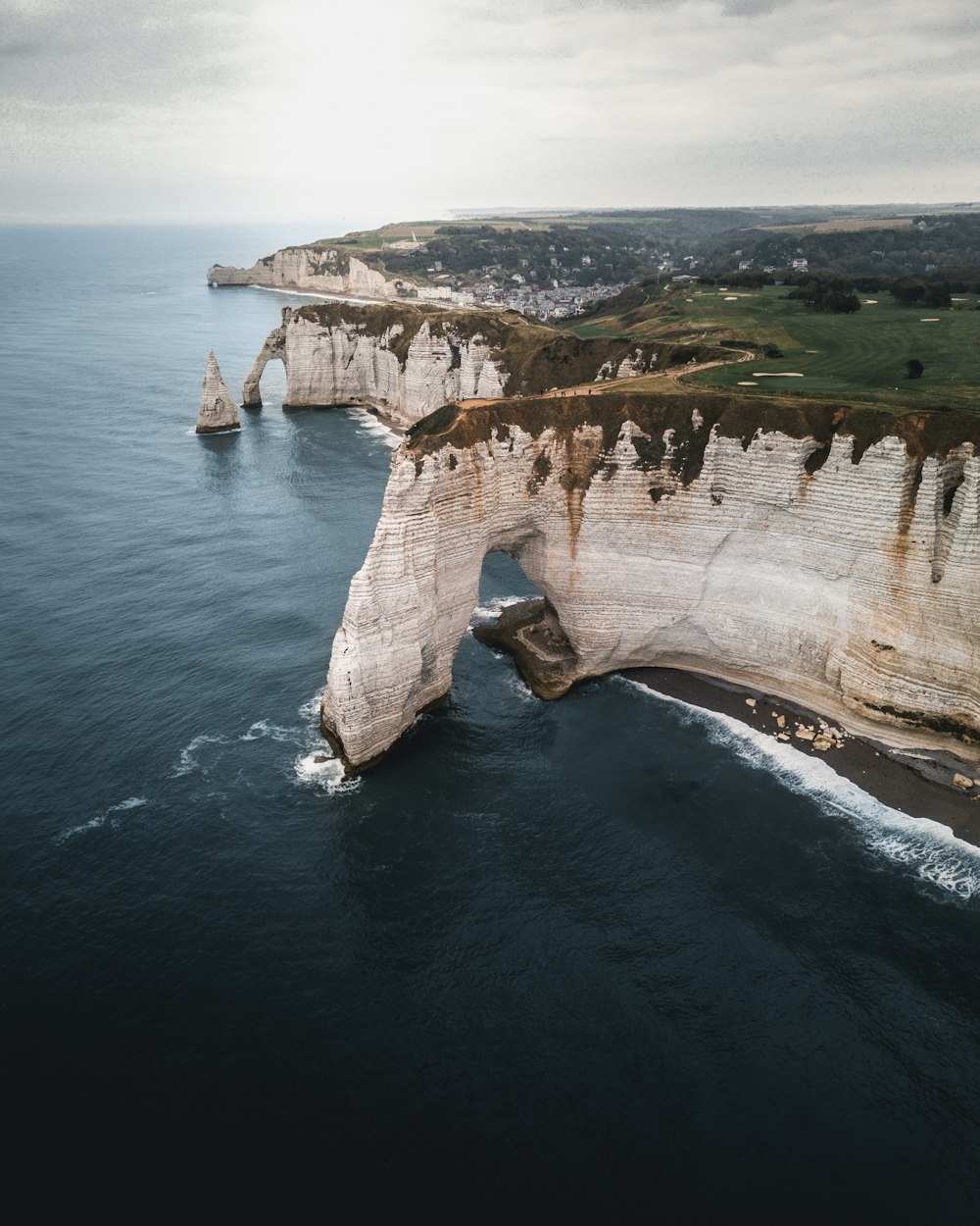 brown and green cliff and body of water