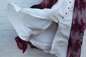 Artistic capture of flowing fabrics in motion against a stark white background with subtle burgundy accents