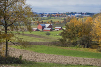A scenic Vermont farm landscape at sunset, with rolling hills and a red barn in the distance.