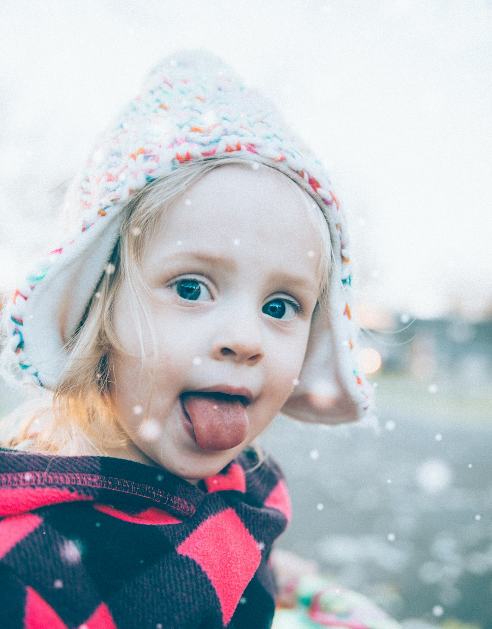 menina usando boné de malha e mostrando sua língua