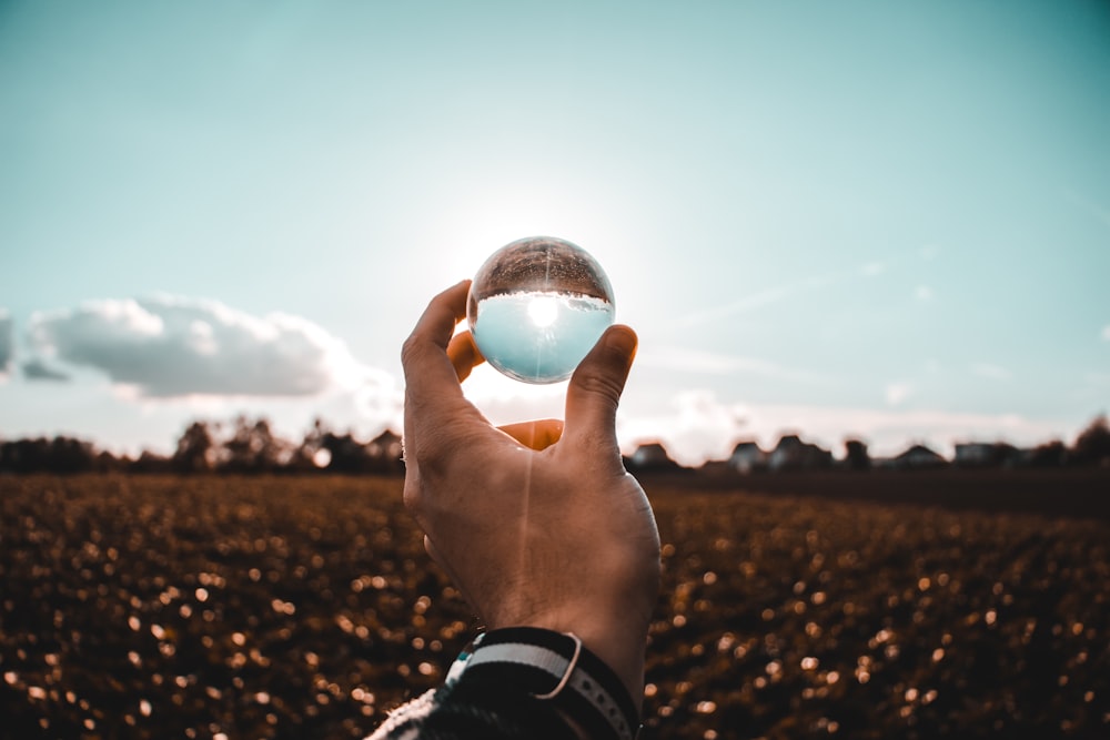 personne tenant une boule de verre transparent