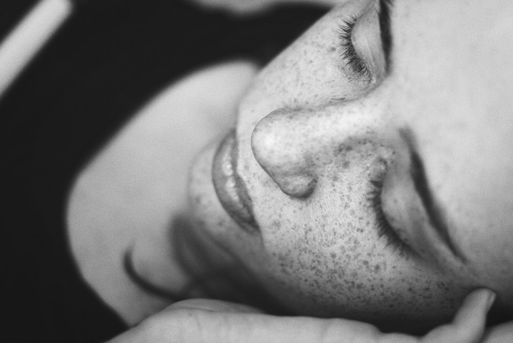 Foto in scala di grigi del viso della donna con lentiggini