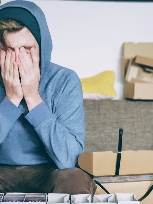 man covering face with both hands while sitting on bench