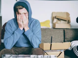 man covering face with both hands while sitting on bench