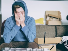 man covering face with both hands while sitting on bench