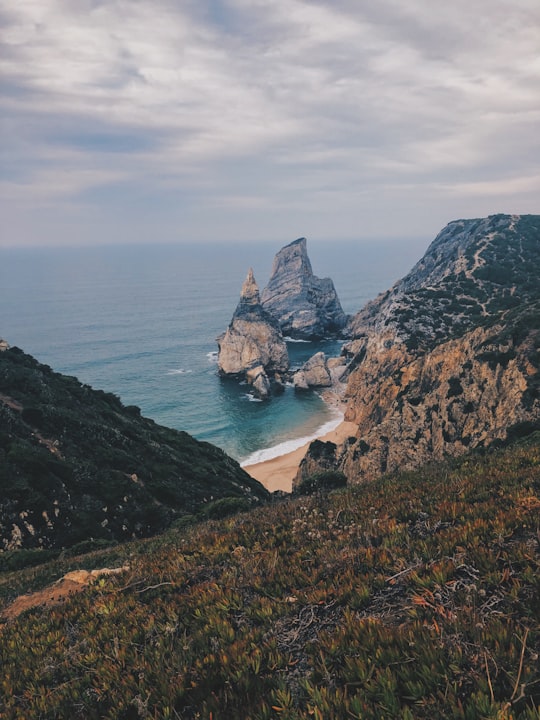 aerial photography of rock islets near white sand beach in Sintra-Cascais Natural Park Portugal