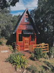 A charming wooden accommodation wendy house with a small porch and curtains.