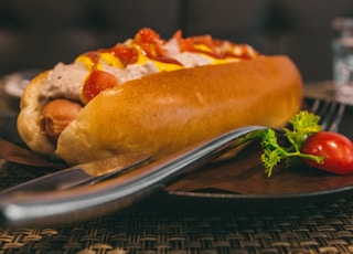 burger on black plate beside gray stainless steel dining fork