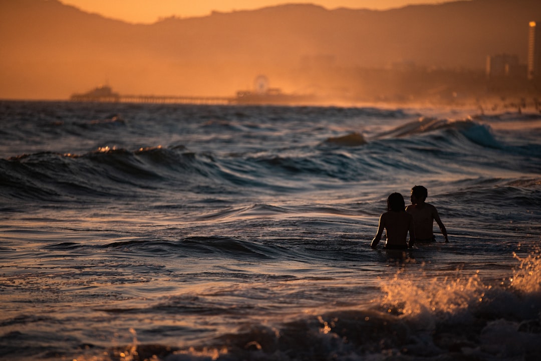 man and woman swimming in ocean at golden hour