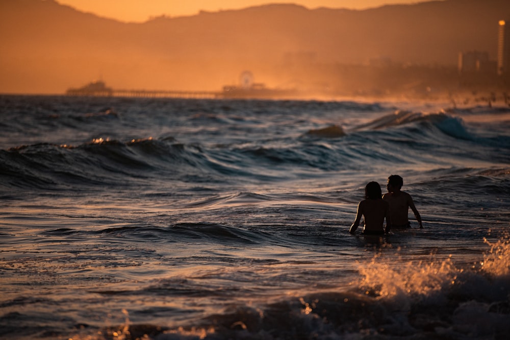 Hombre y mujer nadando en el océano en la hora dorada