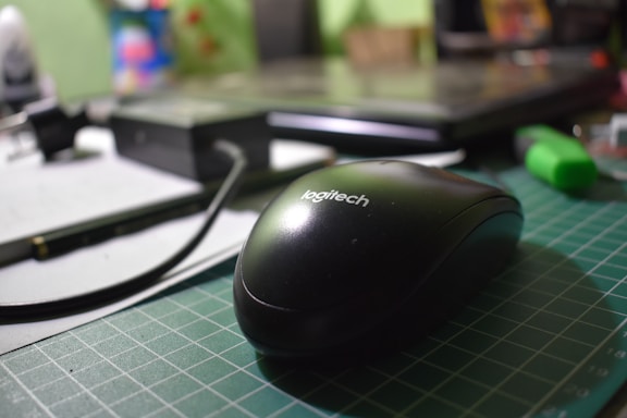 Close-up of a Logitech G309 mouse on a sleek desk with soft lighting.