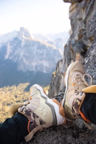 person sitting on rock near gray fault-block mountain