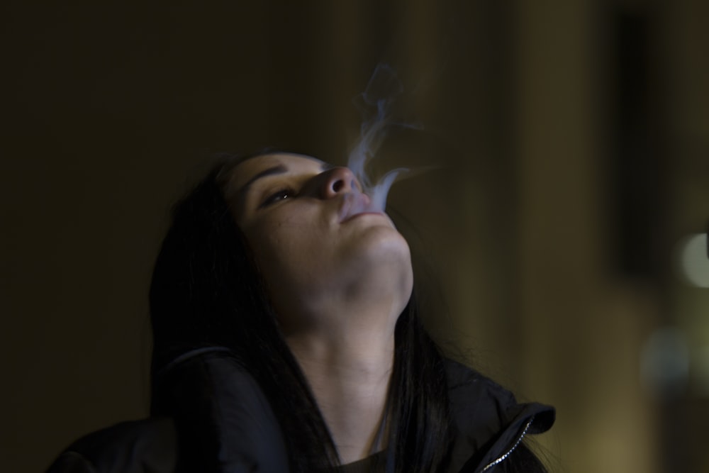 Frau steht beim Rauchblasen