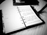 A blurred photo of an old notebook filled with sketches and notes.