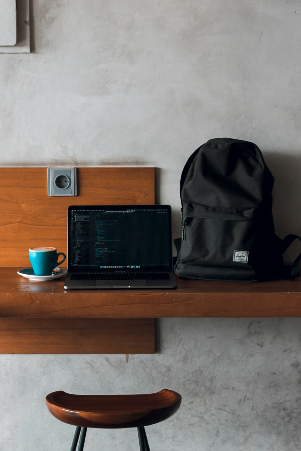 computador portátil ao lado da mochila e caneca de café