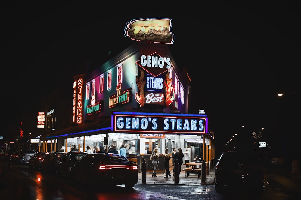 people standing and walking near Geno's steak building during nighttime
