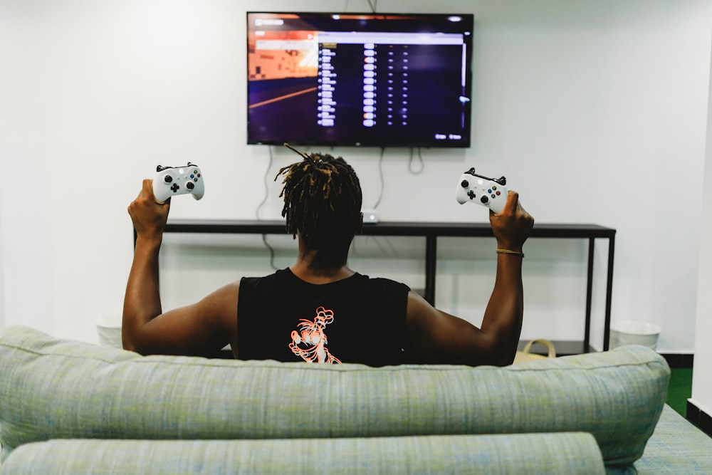 man sitting on couch holding controllers