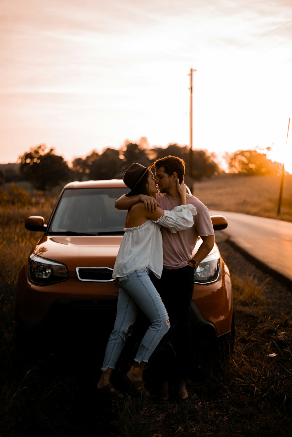 Mujer y hombre de pie frente al vehículo