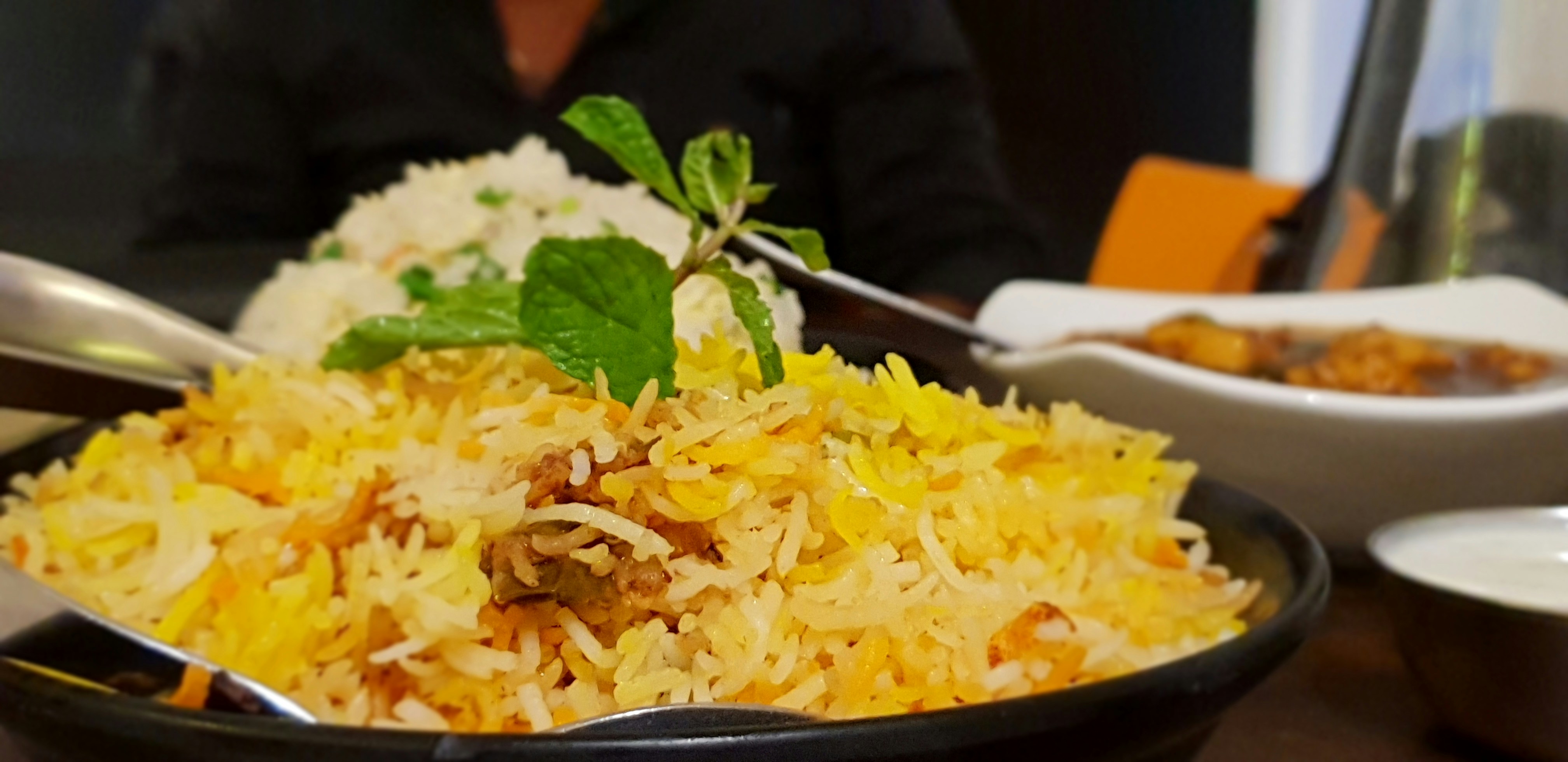 Bright orange biryani rice with whole spices and mint garnish