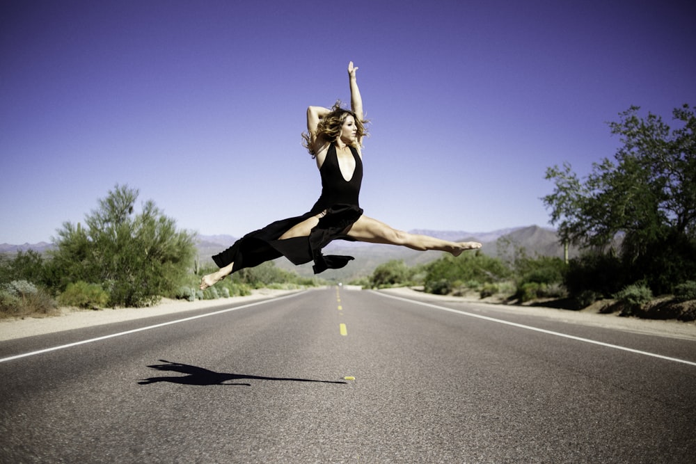 time-lapse photography of woman doing split in air in the middle of road