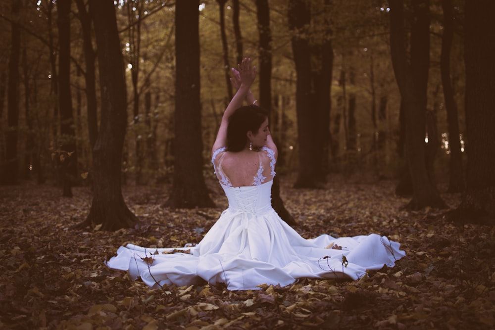 woman in white sleeveless dress sitting on piles of leaves