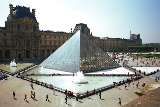 people walking around pyramid landmark in Louvre France