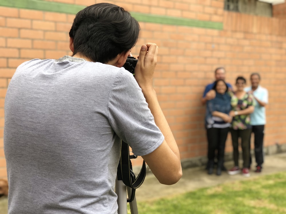 homme prenant une photo à quatre personnes debout à côté du mur