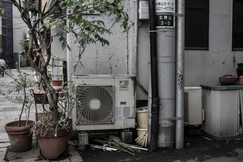Outdoor condenser unit positioned beside potted plants in a courtyard