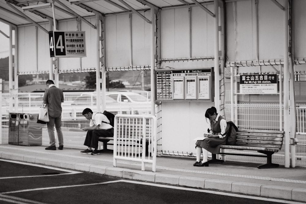 students sitting on bench near bus stop