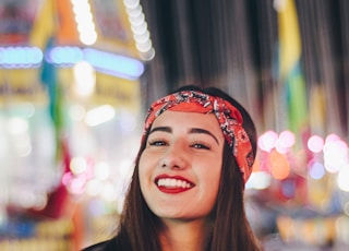 selective focus photography of smiling woman wearing red and black bandana