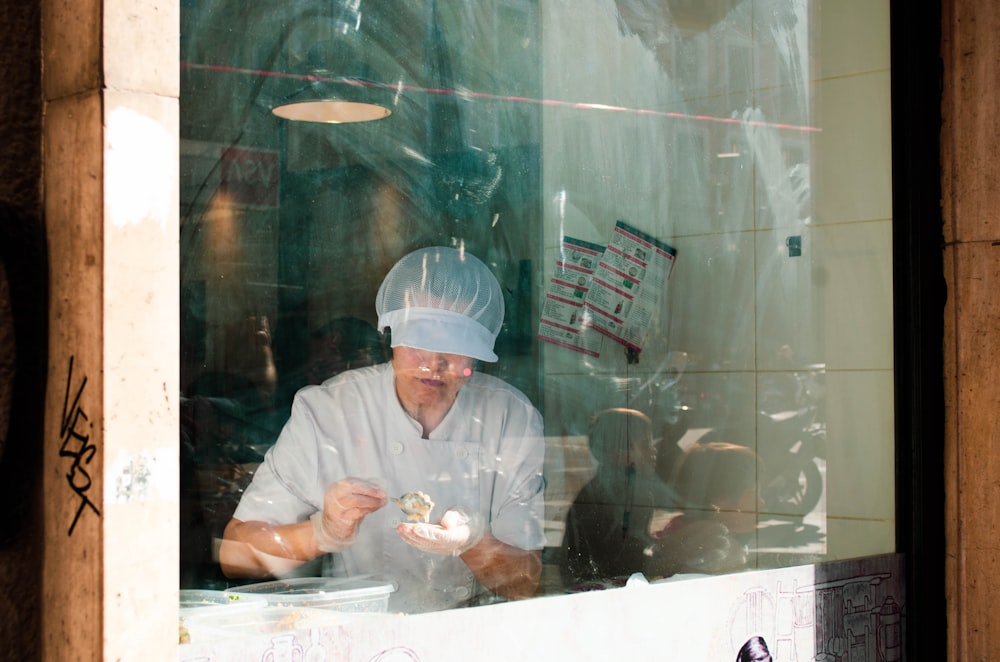 person standing and holding food near window