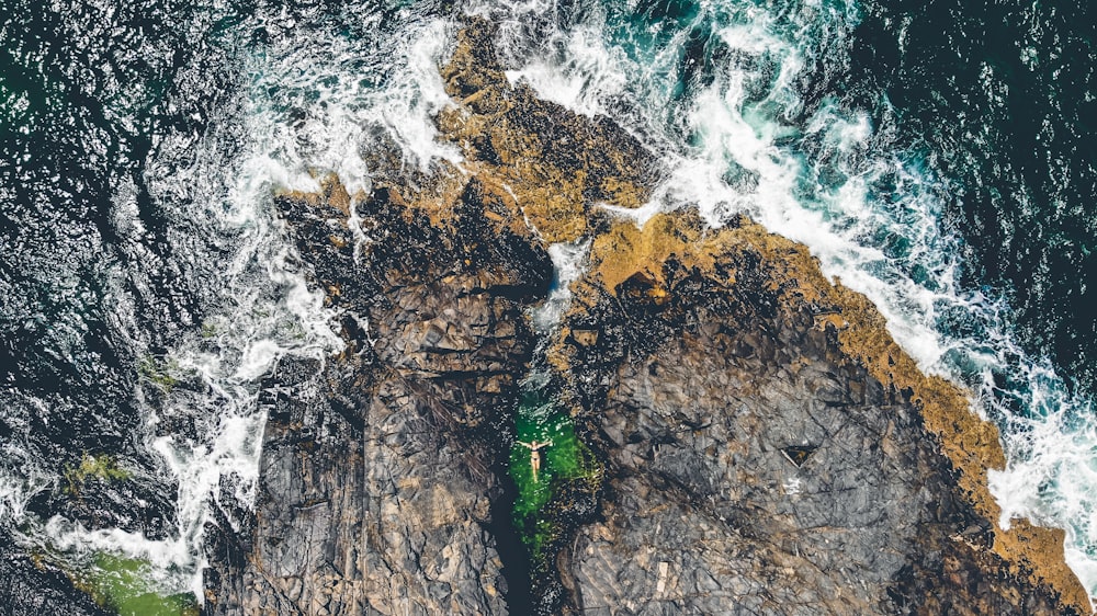 persona flotando en un cuerpo de agua entre rocas