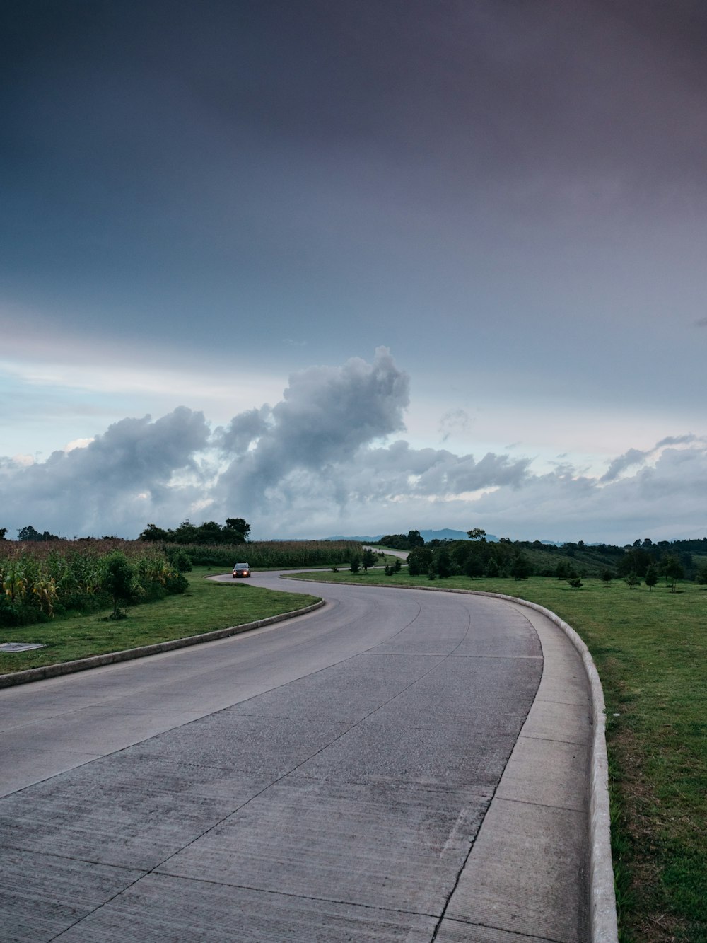 car passing on zig zag road during cloudy sky