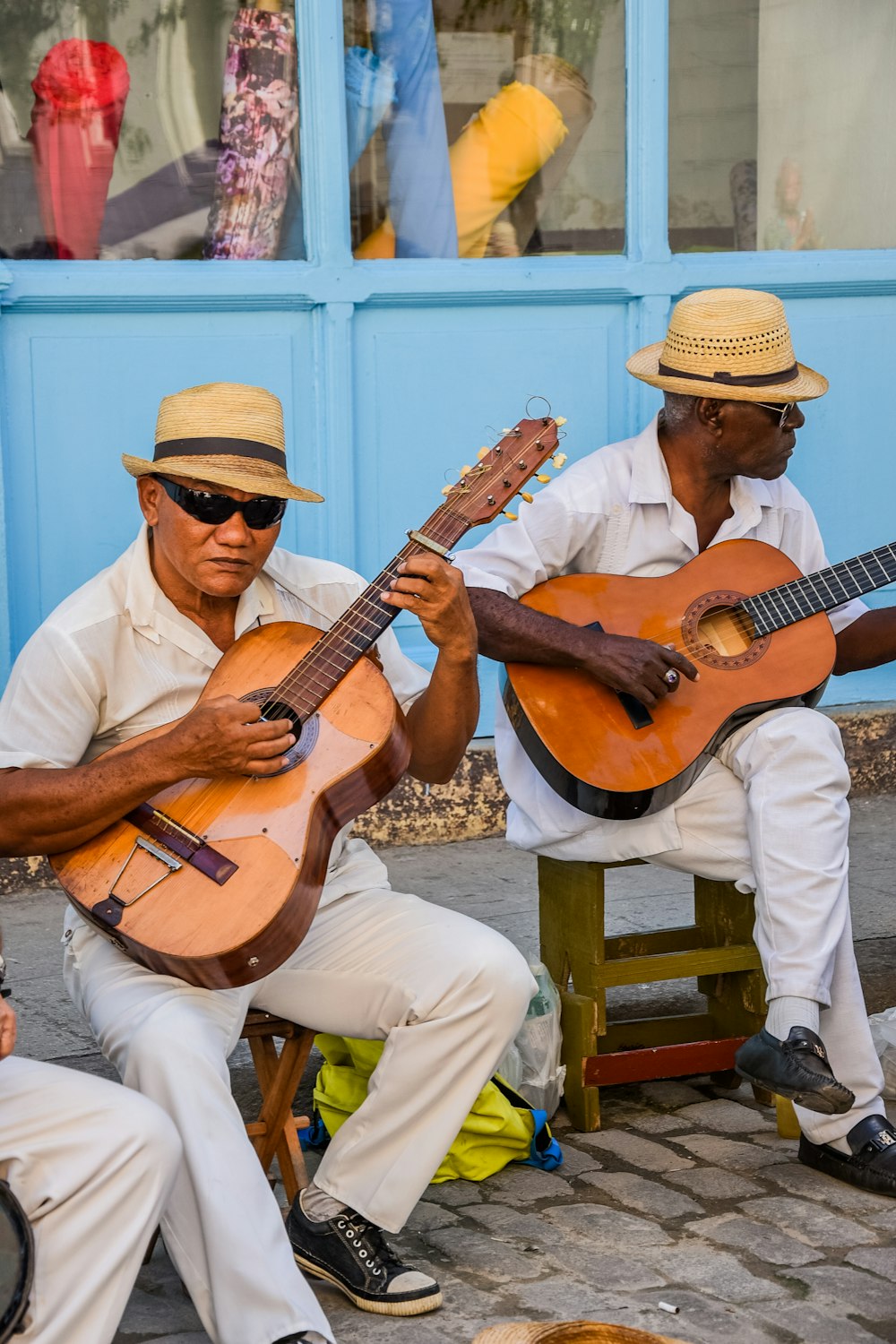two men sitting on a bench playing guitars