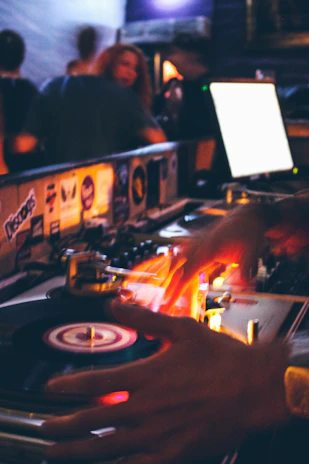 Close-up of a DJ spinning vinyl records under neon lights at a downtown club.