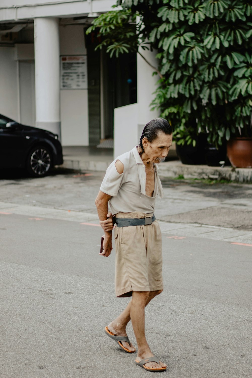 uomo che indossa pantaloncini marroni in piedi sulla strada di cemento