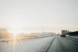 A Fortis Tow truck assisting a stranded vehicle on a snowy Fort McMurray road at sunset.