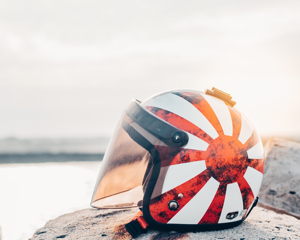 close-up photo of white and red Japanese sun flag helmet on top rock