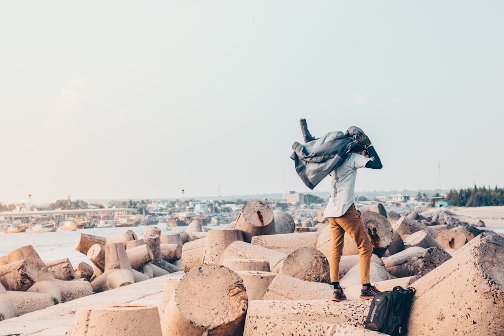 man carrying jacket on rocks