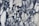 A marble surface displaying intricate black and white veining patterns with a few subtle hints of green. The design features irregular, jagged shapes interwoven amidst a backdrop of creamy white.