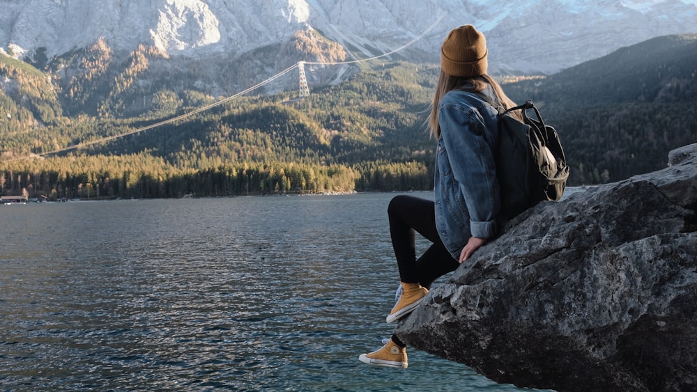 woman sitting on cliff during daytime