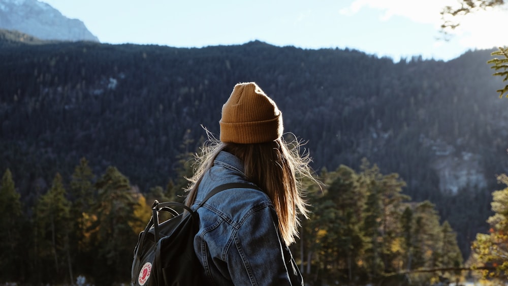 woman wearing blue denim jacket overlooking green forest