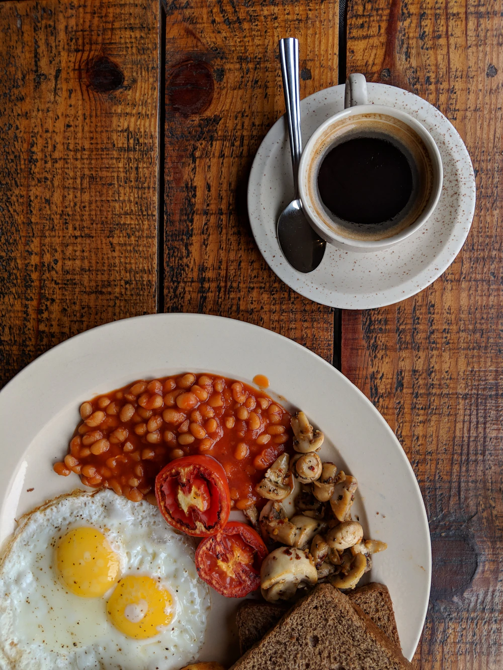 A cooked breakfast with eggs, beans, tomatoes and mushrooms
