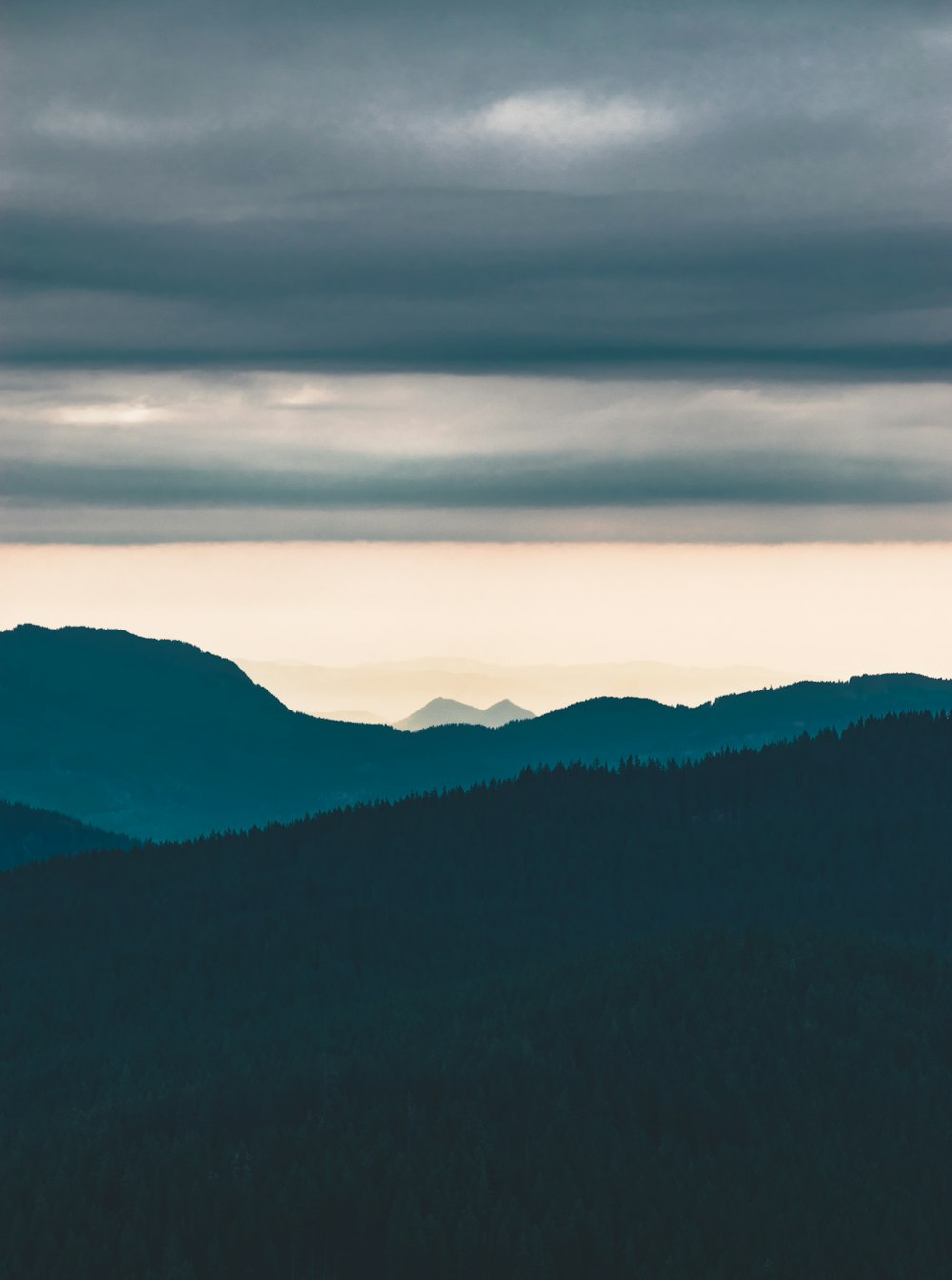 grey clouds over silhouette of tree covered hill