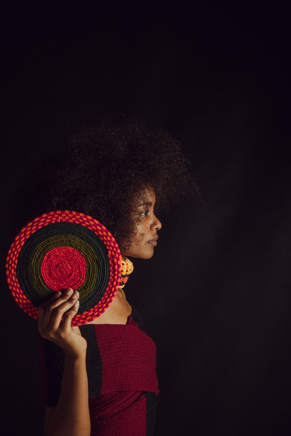 woman wearing maroon and black top holding round black and red decor